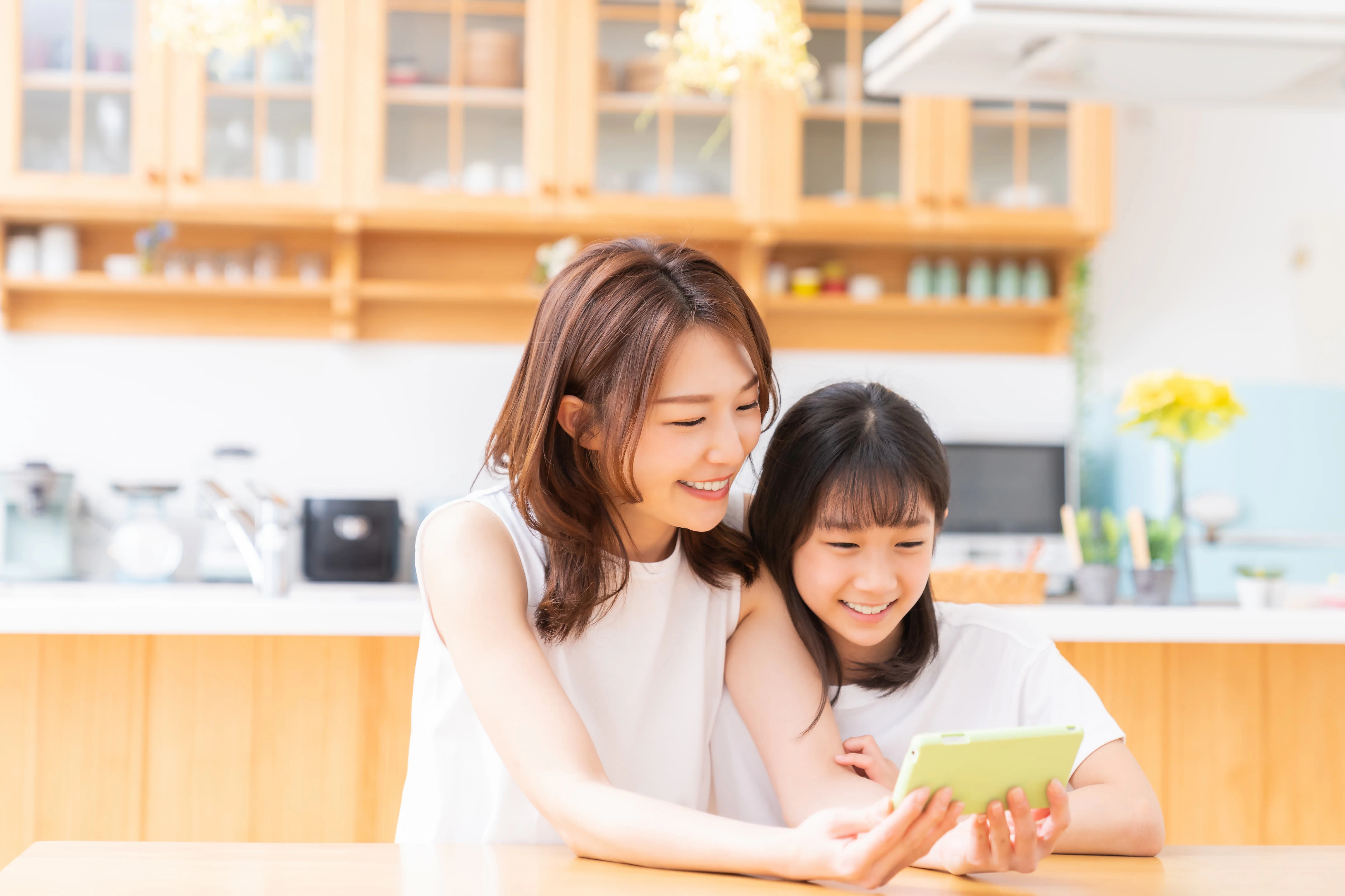 キッチンでスマホを見つめる親子